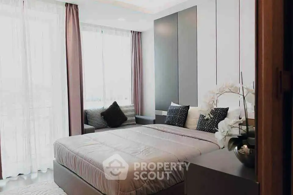 Elegant bedroom with modern decor, large windows, and cozy seating area, perfect for relaxation.
