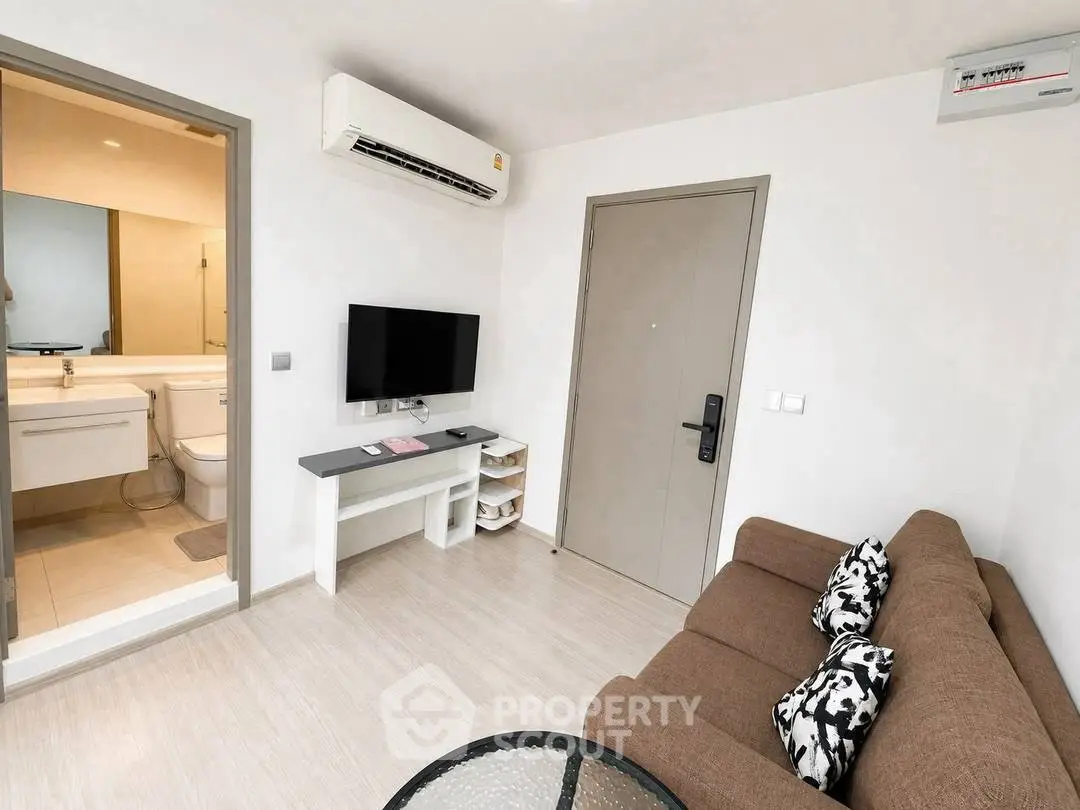Modern living room with air conditioning and TV, adjacent to a bathroom, showcasing sleek design and comfort.