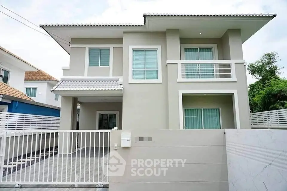 Modern two-story house with sleek design and gated entrance in a suburban neighborhood.