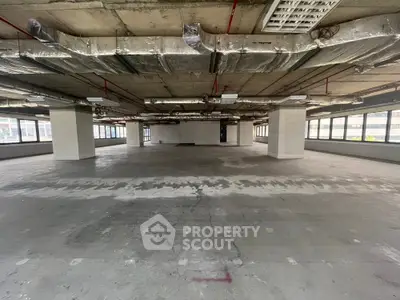 Spacious open-plan commercial space with large windows and exposed ceiling.