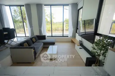 Spacious modern living room with large windows and stylish furniture, offering a bright and inviting atmosphere.