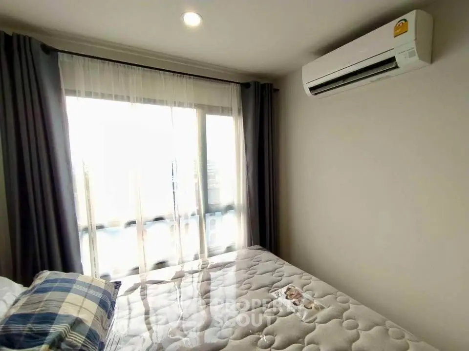 Cozy bedroom with natural light, featuring a comfortable bed and modern air conditioning unit.
