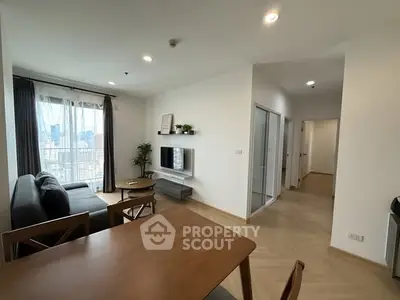 Modern living room with city view, stylish furniture, and natural light.