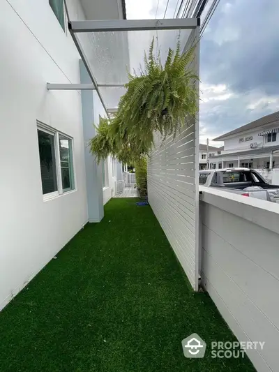 Modern exterior with lush greenery and artificial grass in a stylish residential area.