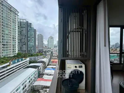 High-rise city view with balcony featuring washing machine and urban skyline.