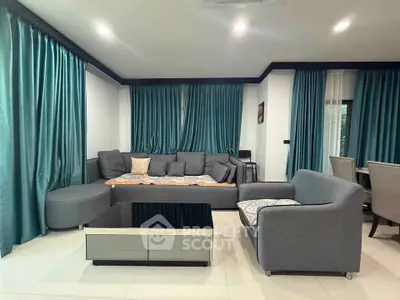 Spacious living room with modern gray furniture and elegant teal curtains, perfect for relaxation and entertaining.