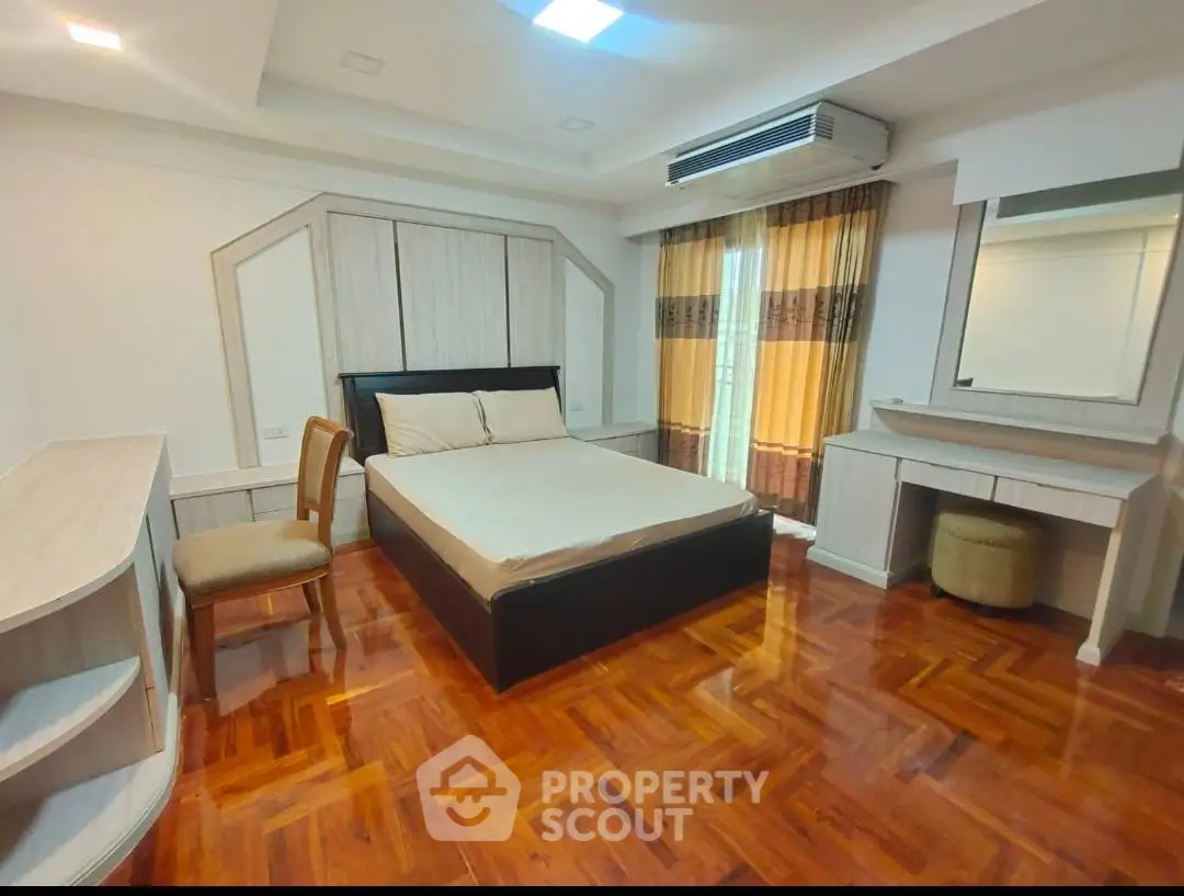 Spacious bedroom with elegant wooden flooring and modern furnishings