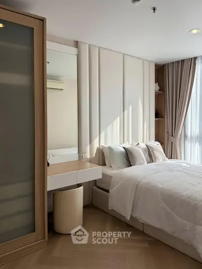 Elegant bedroom with natural light, modern decor, and cozy bedding in a stylish apartment.
