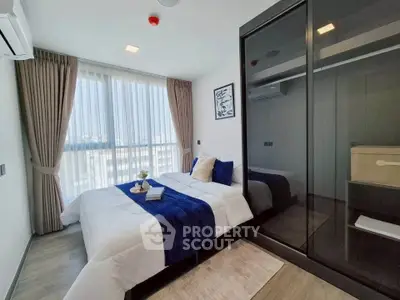 Modern bedroom with large window and stylish decor in a contemporary apartment.