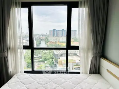 Bright bedroom with large window offering stunning city view, perfect for urban living.
