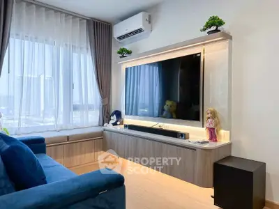 Modern living room with large TV, stylish shelving, and cozy seating area with natural light.