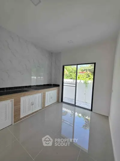 Spacious kitchen with sleek cabinetry and large glass doors opening to a serene outdoor view.