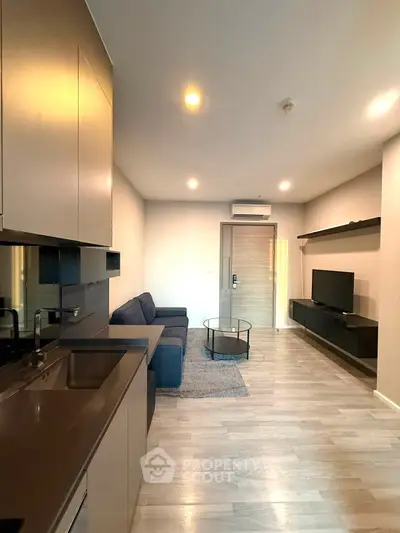 Modern living room with sleek kitchen and cozy seating area in stylish apartment.