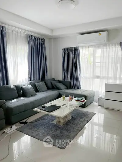 Spacious living room with modern furniture and natural light, perfect for relaxation and entertainment.