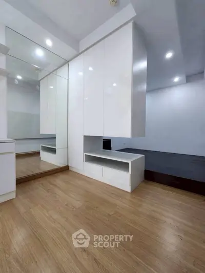 Modern minimalist bedroom with sleek white cabinetry and wooden flooring