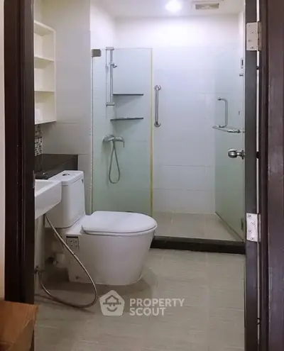 Modern bathroom with glass shower enclosure and sleek fixtures in a contemporary apartment.