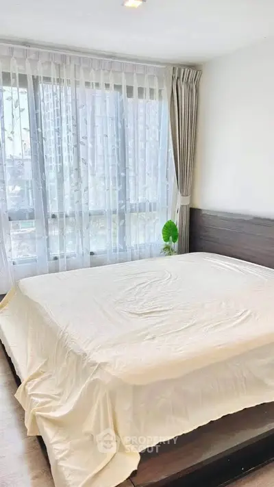 Spacious bedroom with large windows and modern decor in a high-rise apartment.