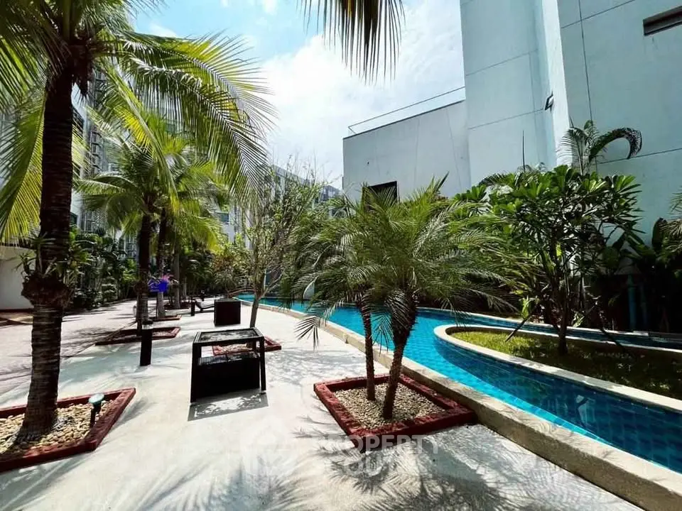 Luxurious tropical garden with poolside view in modern residential complex.