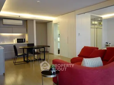 Modern living room with red sofa and dining area in open layout apartment.