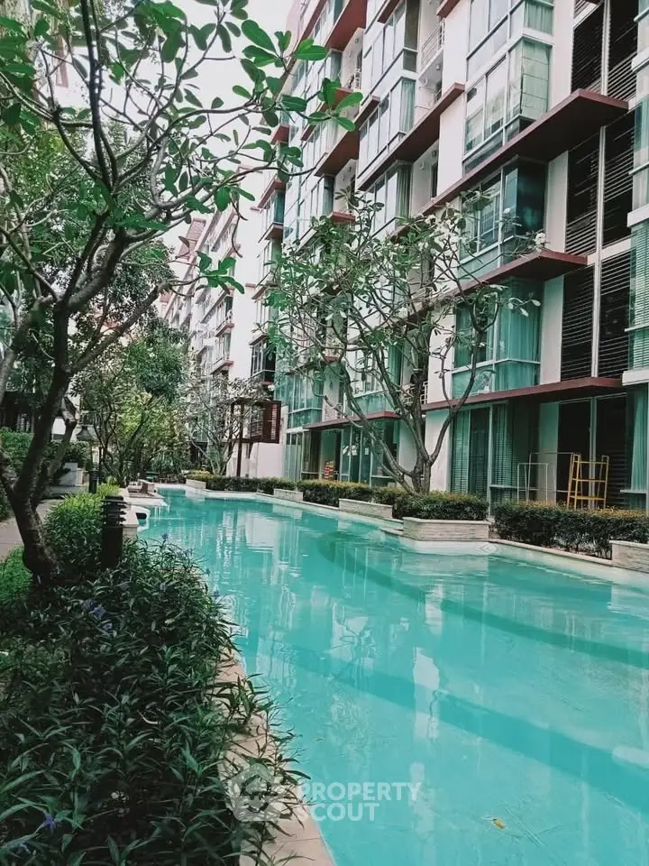 Luxurious apartment complex with serene pool and lush greenery
