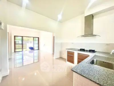 Spacious kitchen with granite countertops and open layout leading to bright living area.