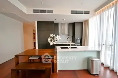 Modern kitchen with sleek design, featuring a wooden dining table and marble island.