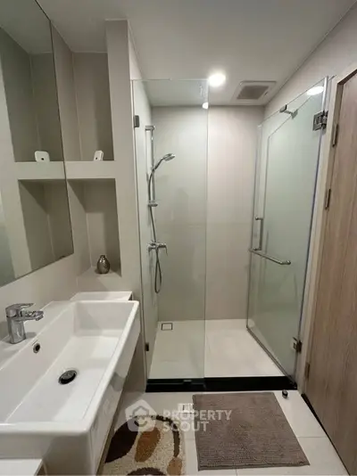Modern bathroom with glass shower enclosure and sleek fixtures.
