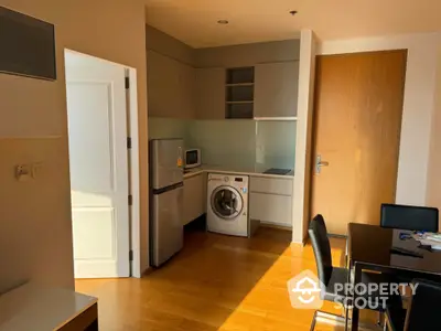 Modern kitchen with washing machine and dining area in cozy apartment