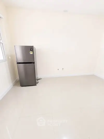 Spacious empty room with sleek stainless steel refrigerator, ideal for modern kitchen setup.