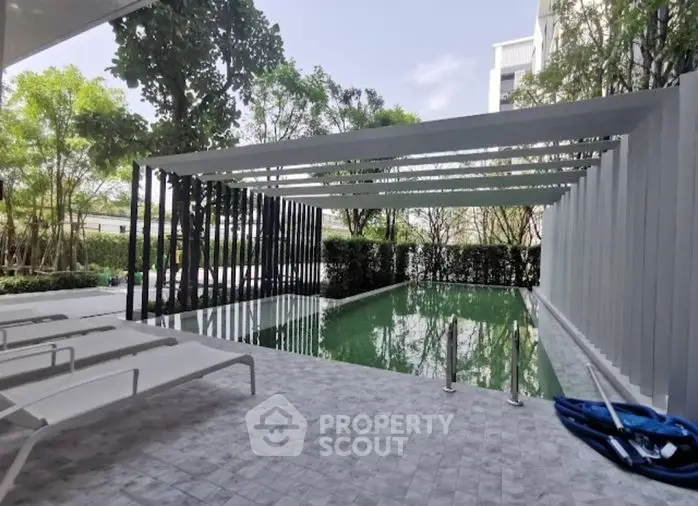 Inviting modern pool area with elegant loungers, shaded pergola, and lush greenery, perfect for relaxation and entertainment.