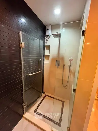 Modern bathroom with glass shower enclosure and sleek black tile accent wall.