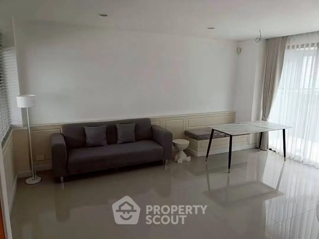 Spacious living room with modern sofa and natural light in a stylish apartment.