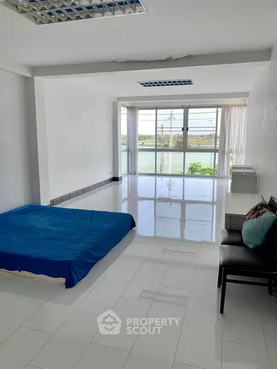 Spacious minimalist bedroom with large windows and scenic river view.
