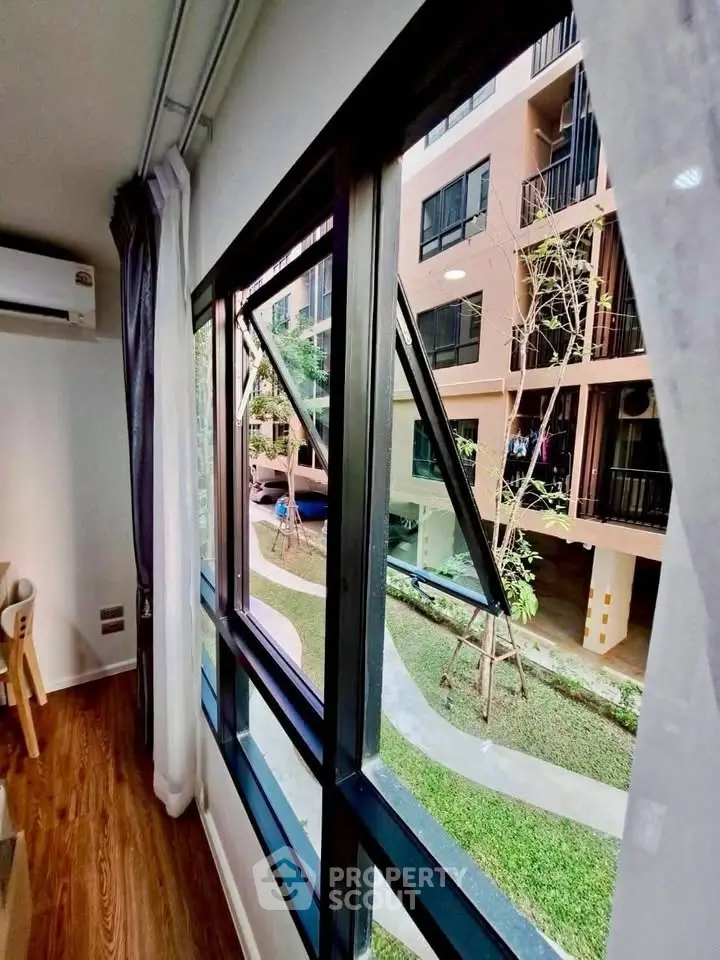 Modern apartment window view with lush garden and building exterior