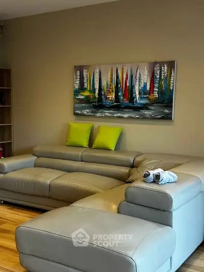 Modern living room with stylish leather sofa and vibrant sailboat artwork, perfect for relaxation and entertaining.
