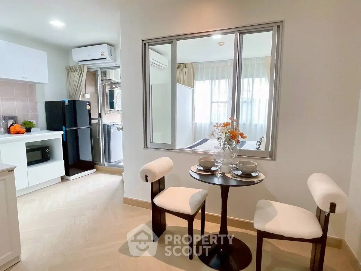 Modern apartment interior with dining area and kitchen featuring sleek appliances.