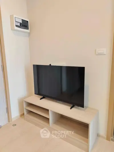 Modern living room with sleek TV setup and minimalist wooden stand.
