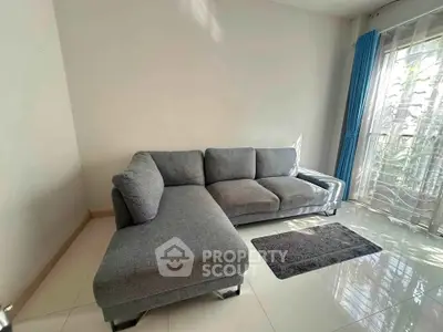 Spacious living room with modern gray sectional sofa and large window for natural light.