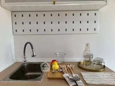 Modern kitchen sink with stylish faucet and wooden utensils on a sleek countertop.