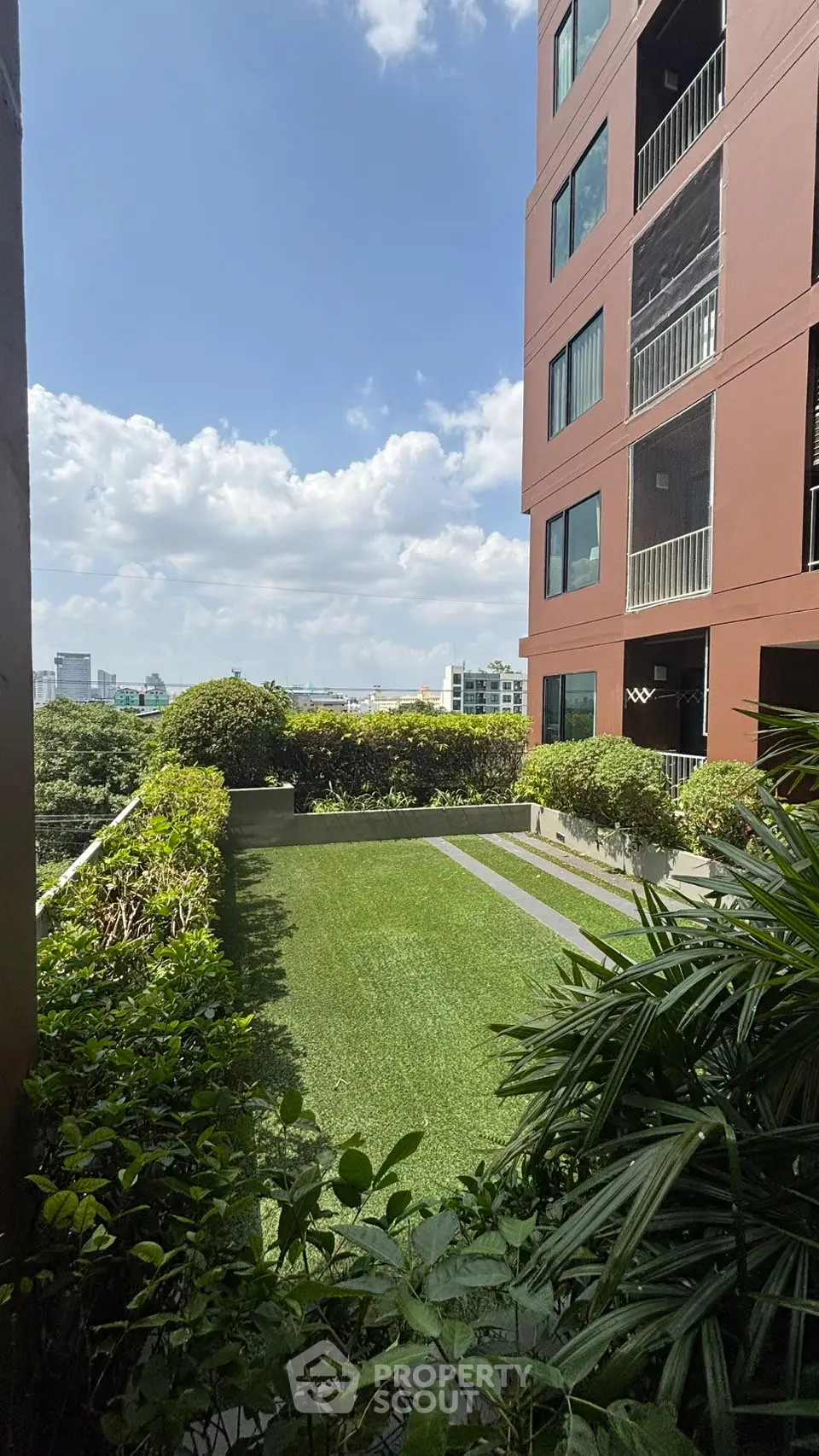 Modern building exterior with lush garden and city view, perfect for urban living.
