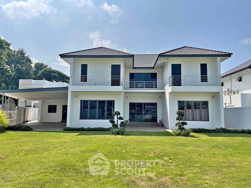 Stunning modern two-story home with lush green lawn and elegant balcony design.