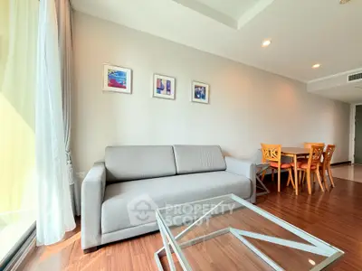 Modern living room with gray sofa, glass coffee table, and dining area in open layout.