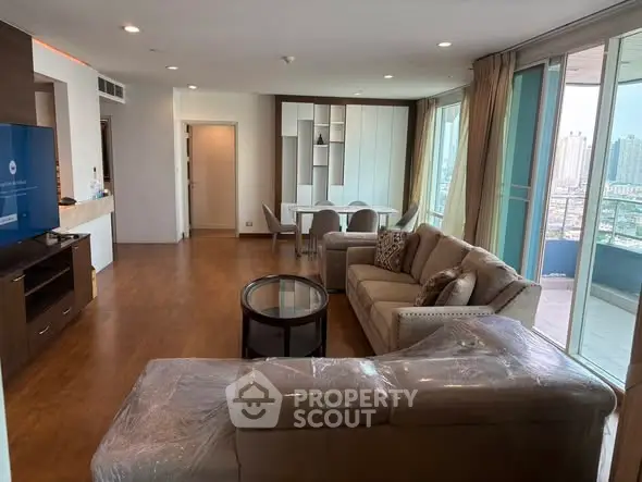 Spacious modern living room with large windows and city view, featuring elegant furniture and open layout.