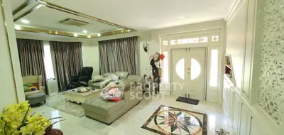 Spacious living room with elegant decor and natural light, featuring comfortable seating and stylish entrance.