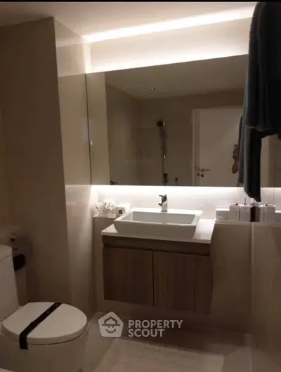 Modern bathroom with sleek fixtures and ambient lighting, featuring a stylish vanity and spacious mirror.