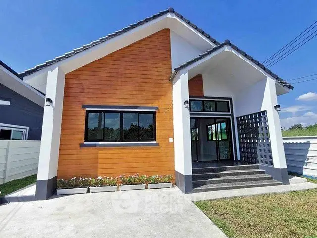 Charming modern house with wooden facade and spacious front yard under clear blue sky.