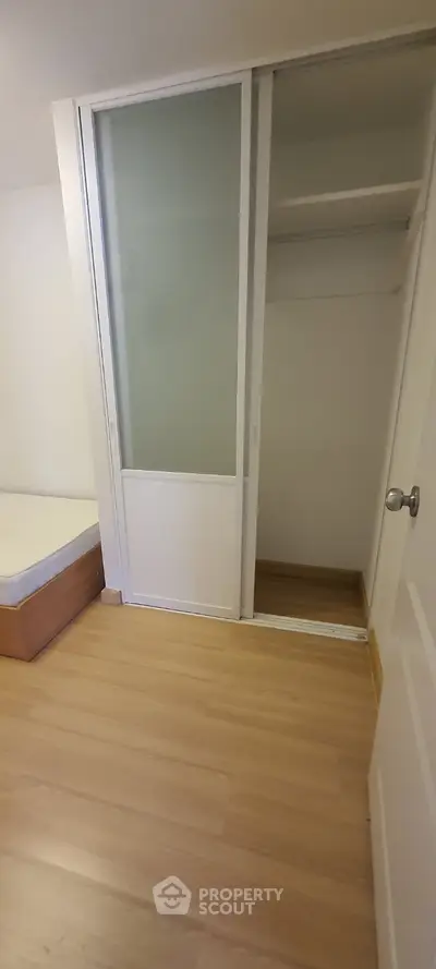 Compact bedroom with sliding closet doors and wooden flooring