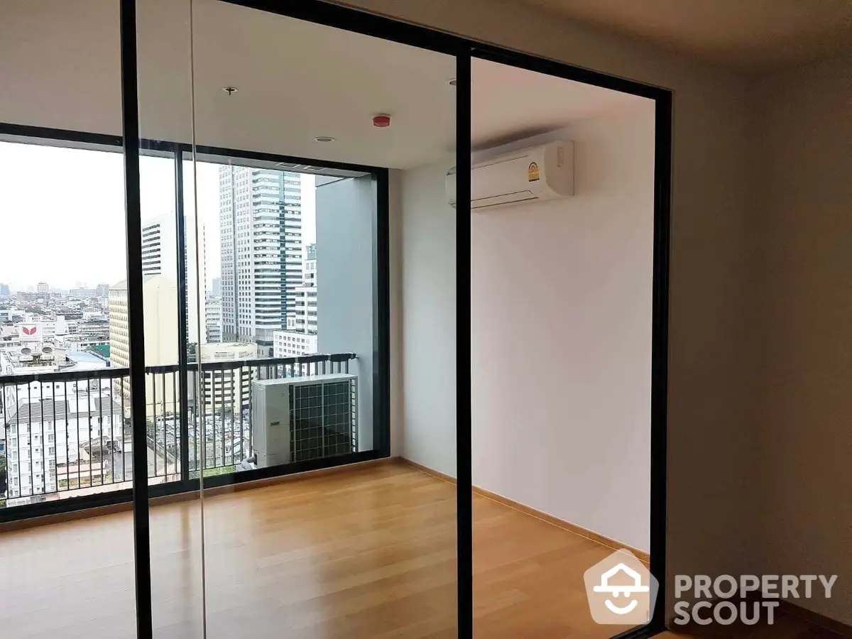 Spacious high-rise corner unit with floor-to-ceiling windows offering panoramic city views and abundant natural light, leading to a large balcony.