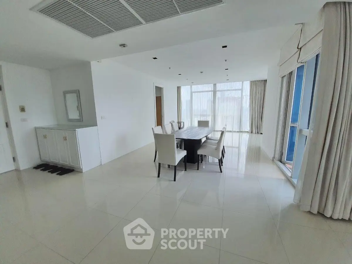 Spacious dining area with elegant table and chairs, large windows offering natural light, and modern minimalist design.