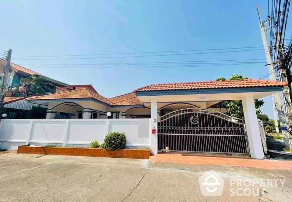 Charming single-story house with gated entrance and tiled roof in a serene neighborhood.